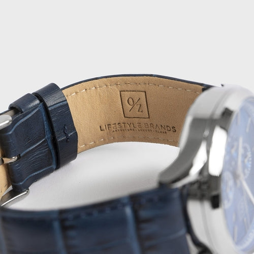 Close-up of a watch with a blue strap and visible brand logo on a white background