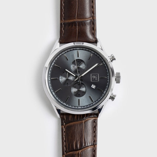 Watch with brown leather strap and gray dial on a light gray background
