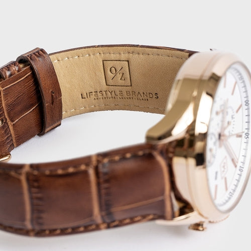 Close-up of a watch with a brown leather strap and gold casing on a white background.