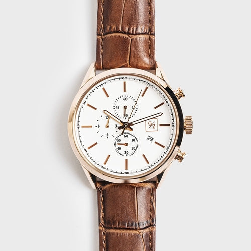 Watch with brown leather strap and white face on light gray background