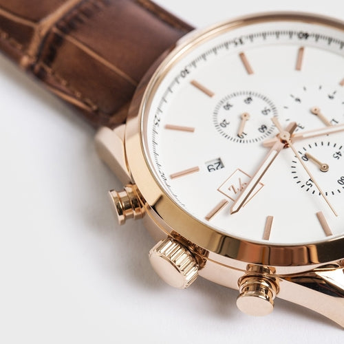 Rose gold watch with a white face on a light background